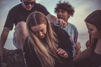 A warm community gathering with smiling youth learning hairstyling outdoors.