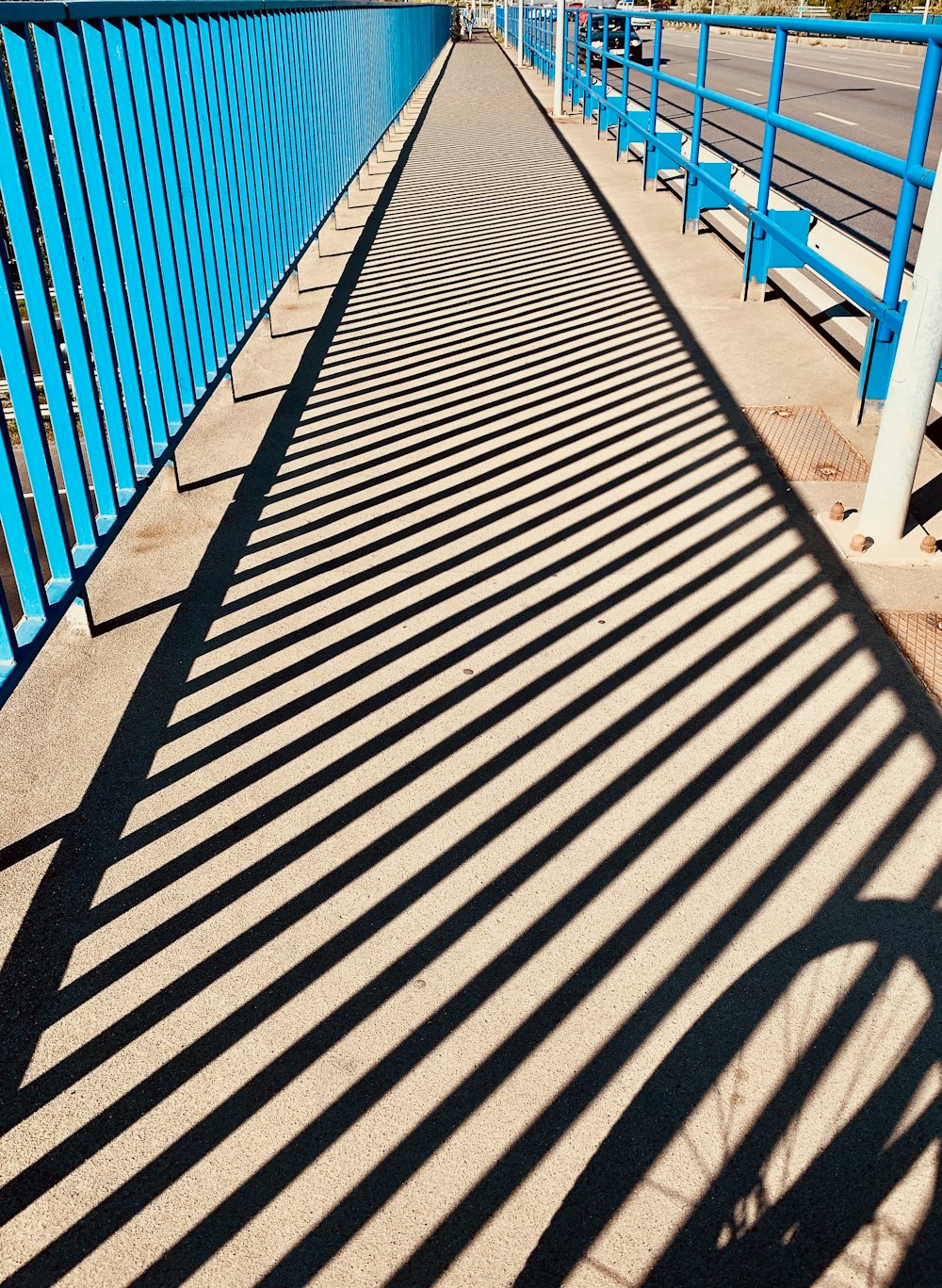 a long blue metal fence next to a street