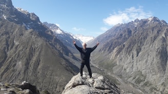 A person standing on a mountain top with arms raised towards the sky.