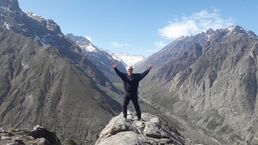 A person standing on a mountain top with arms raised towards the sky.