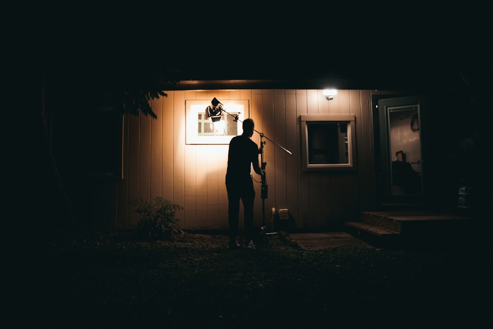 a man standing outside of a house at night