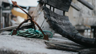 Close-up of weathered hands gripping a heavy iron anchor, symbolizing grounded strength.