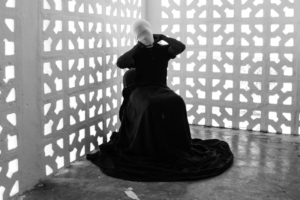 Schaufensterpuppe in schwarzem Kleid sitzt in der Nähe von ausgeschnittenen Wänden