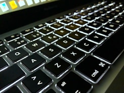 Close-up of a modern laptop with a dark keyboard and illuminated keys.