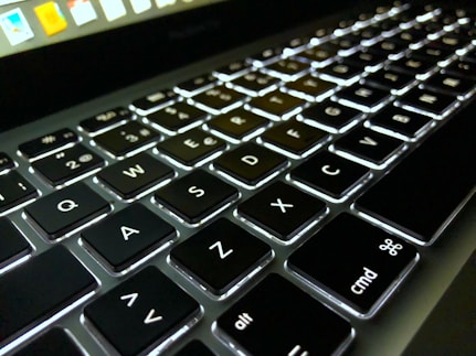Close-up of a modern laptop with a dark keyboard and illuminated keys.