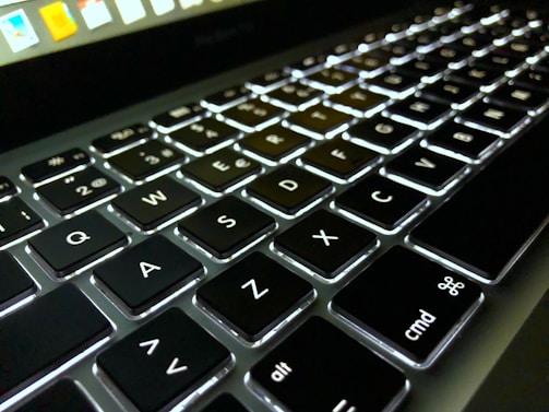 Close-up of a notebook keyboard with backlit keys glowing softly.