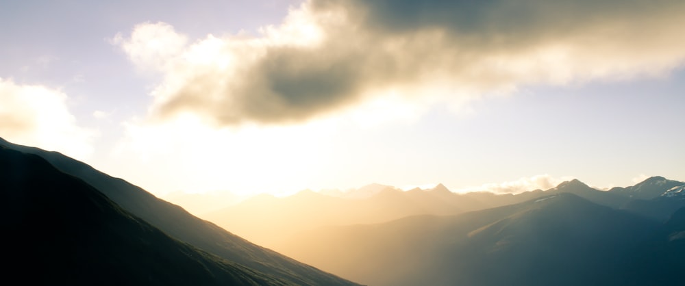 the sun is shining through the clouds over the mountains