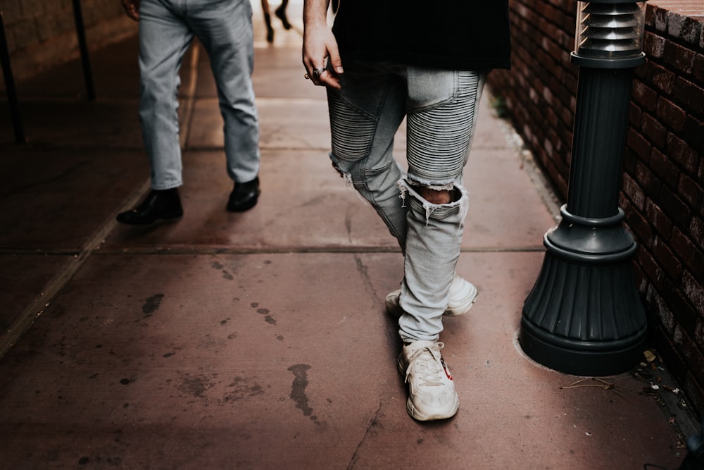 person in gray denim distressed pants