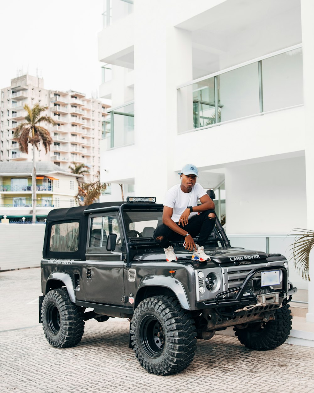 man sitting on vehicle's hood