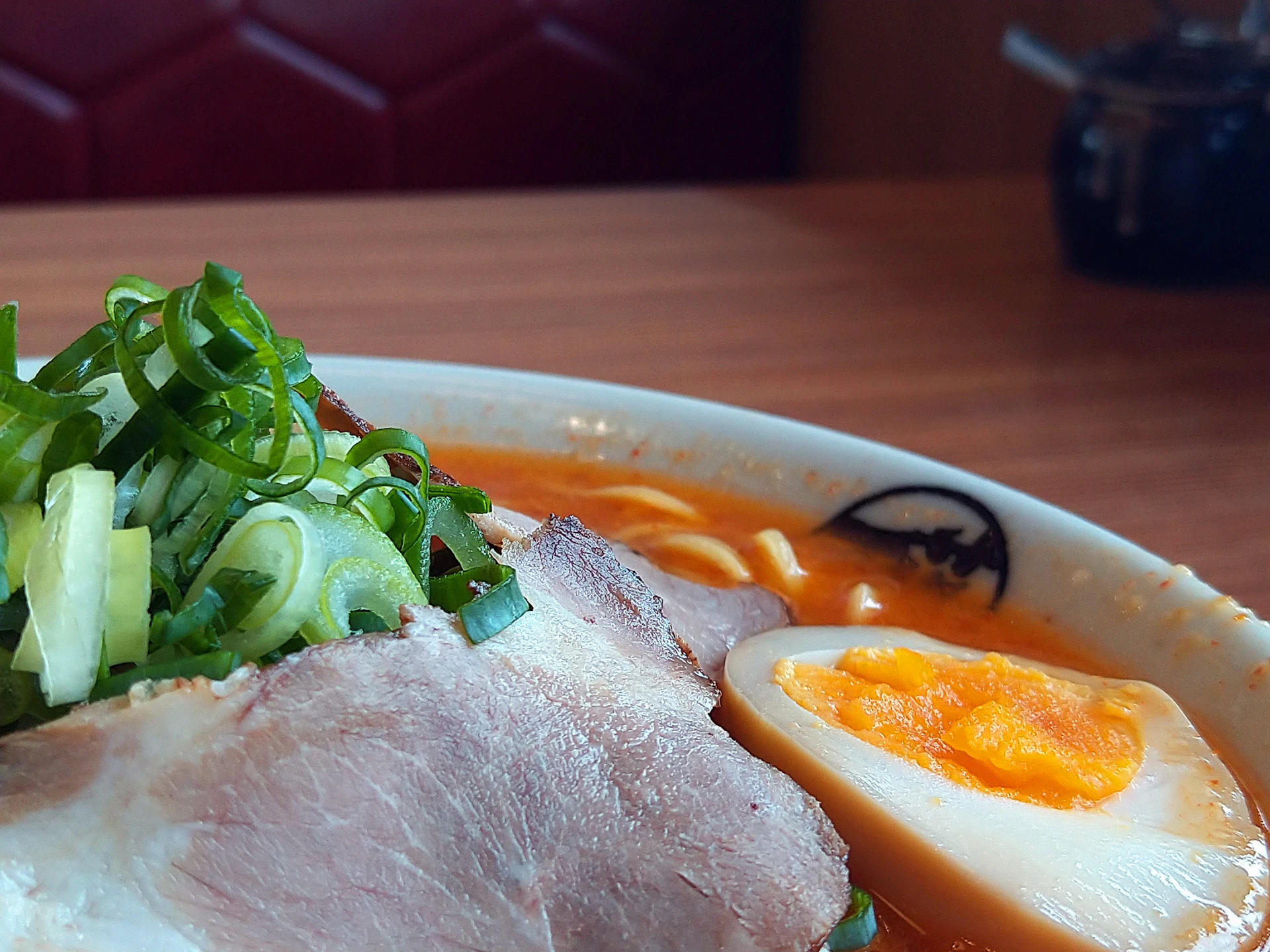 A vibrant close-up of a steaming bowl of ramen with fresh herbs and a perfectly soft-boiled egg.