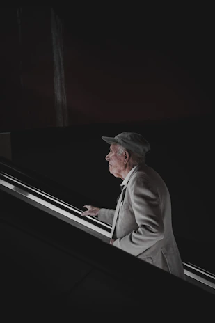 Side view of an elderly person comfortably using the elevita escalator system on a wooden staircase.