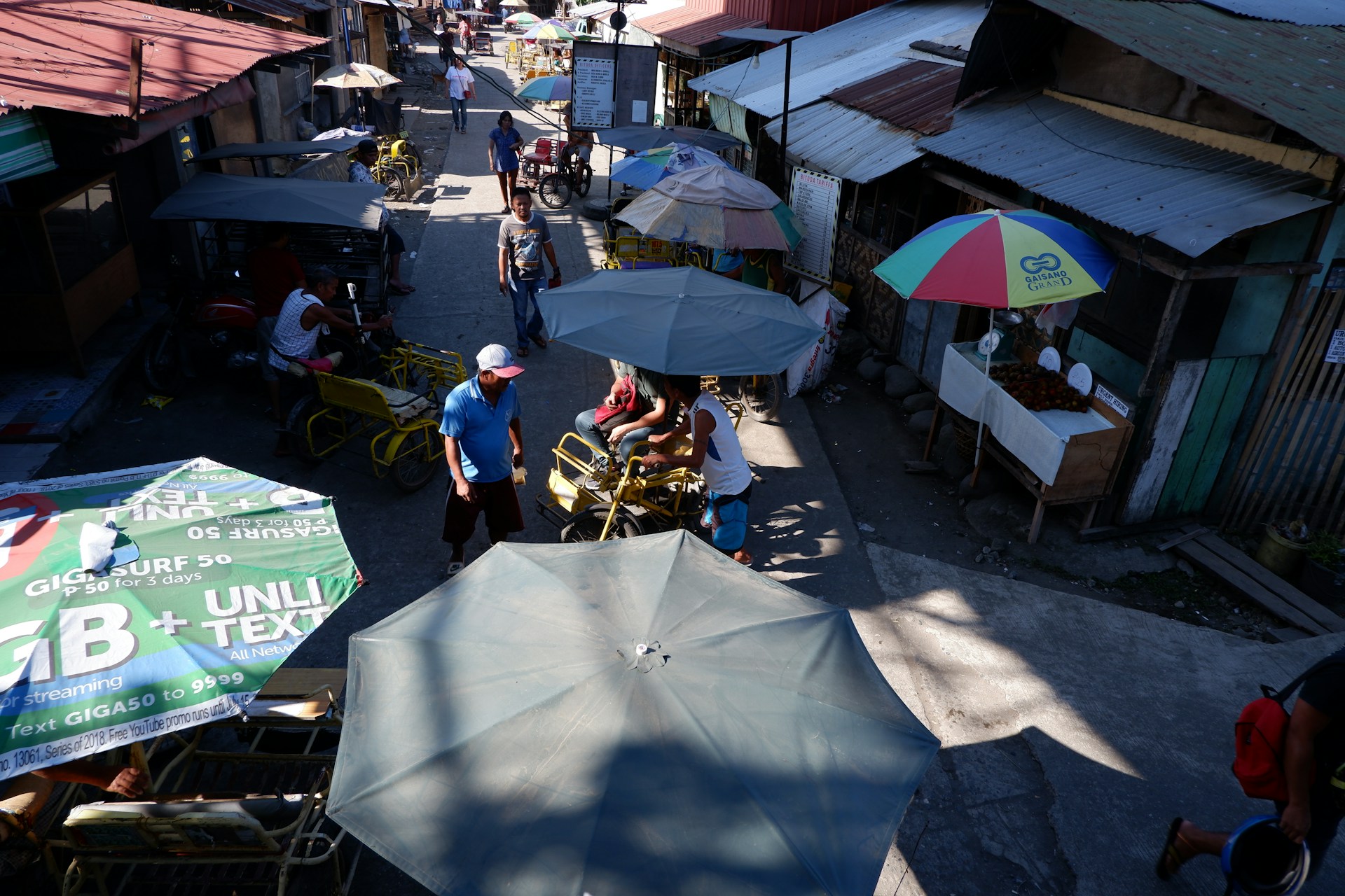 A vibrant street scene capturing a diverse crowd engaged in lively conversation under colorful market umbrellas.