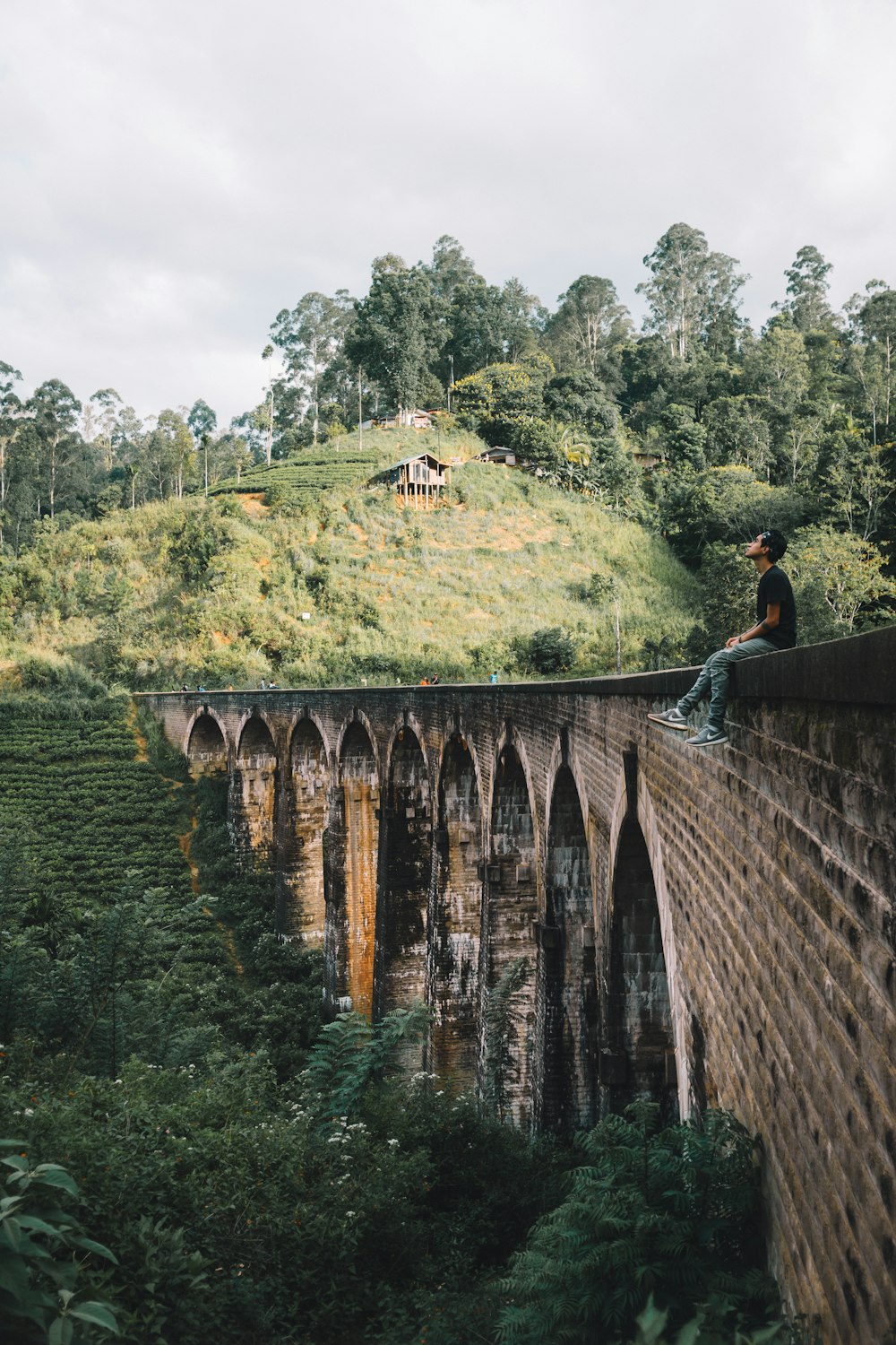 photography of man sitting on bridge during daytime