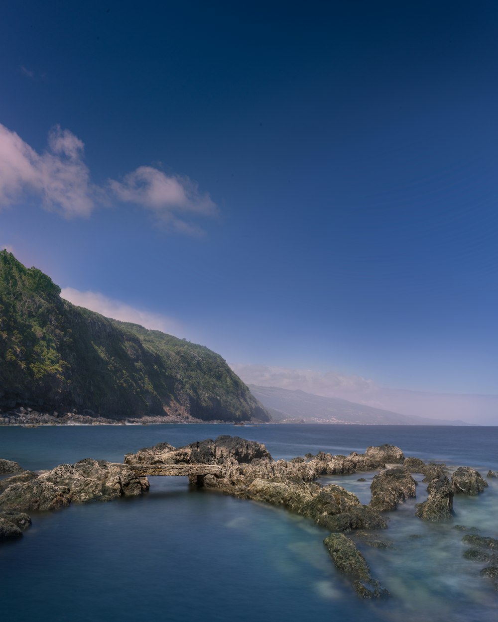 青空の下の水域の岩層