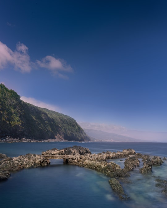 rock formations on body of water under blue sky in Pico Island Portugal