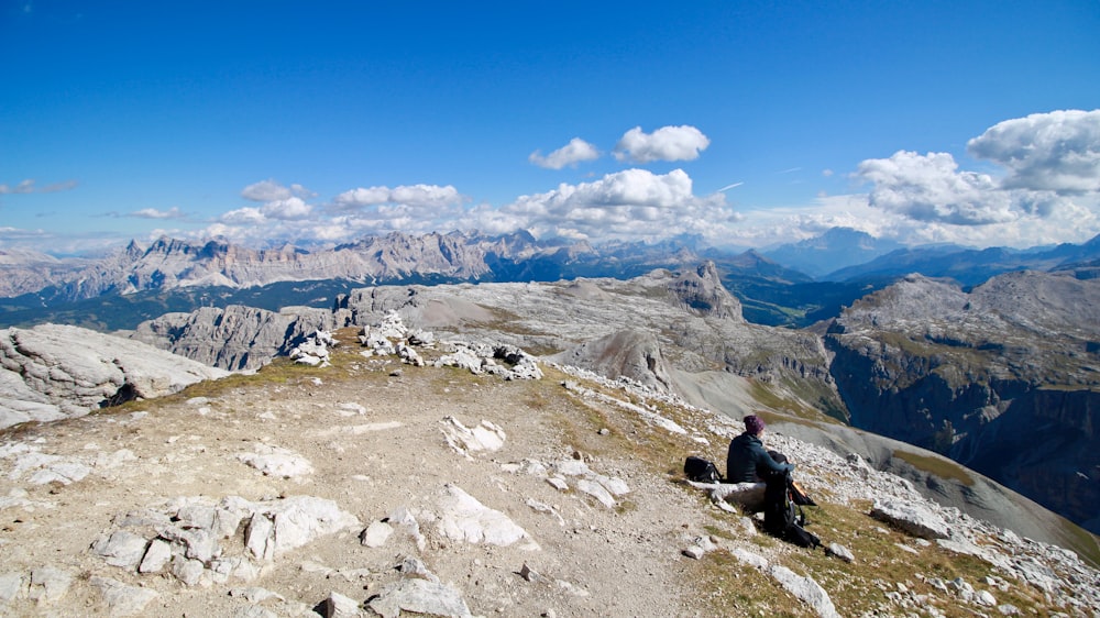 man sitting on rock under blue sky