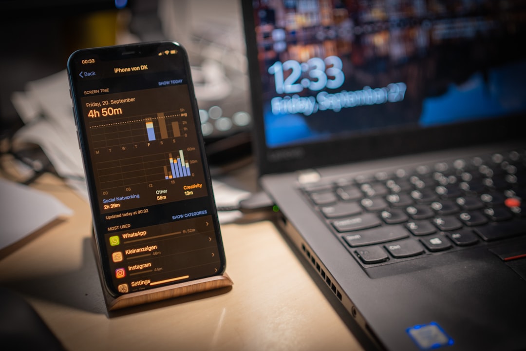 black smartphone beside laptop,