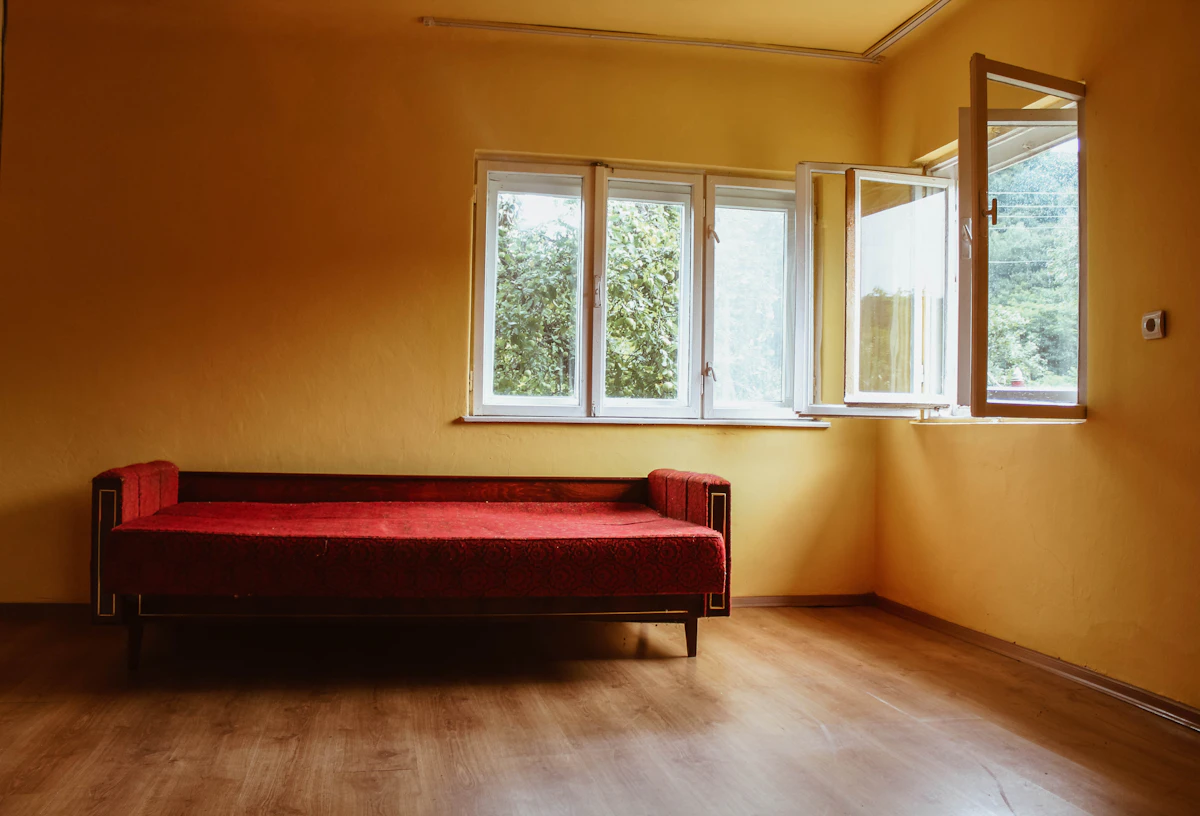 Phòng khách với sofa đỏ đặt cạnh cửa sổ, tường sáng màu - màu sơn nhà hợp mệnh Hỏa
