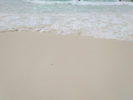 Soft waves washing over smooth sand, leaving delicate patterns that evoke subconscious calm.