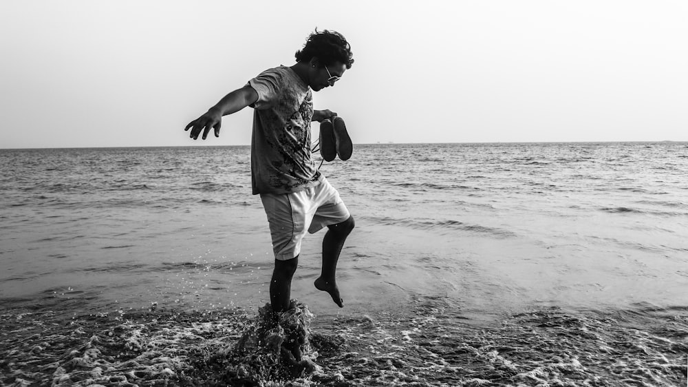 gray-scale photo of man standing on rock