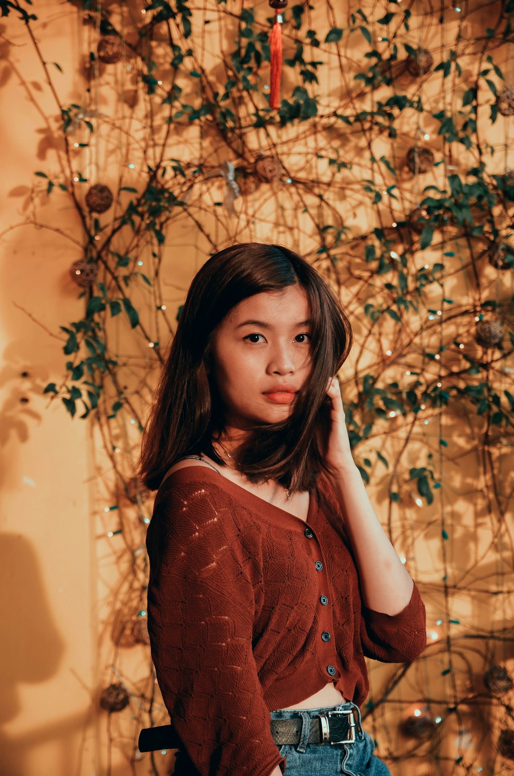 a woman standing in front of a wall with vines on it