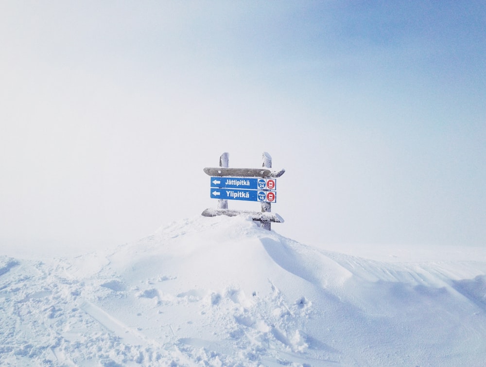 signages on top of hill covered with snow at daytime