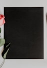 orange rose flower beside notebook and pen