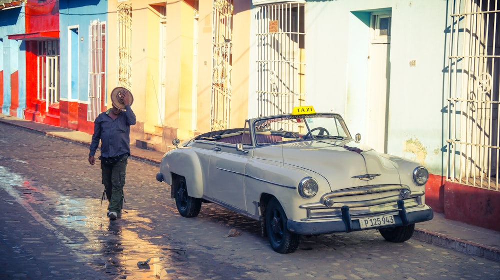 man crossing the street beside a parked car