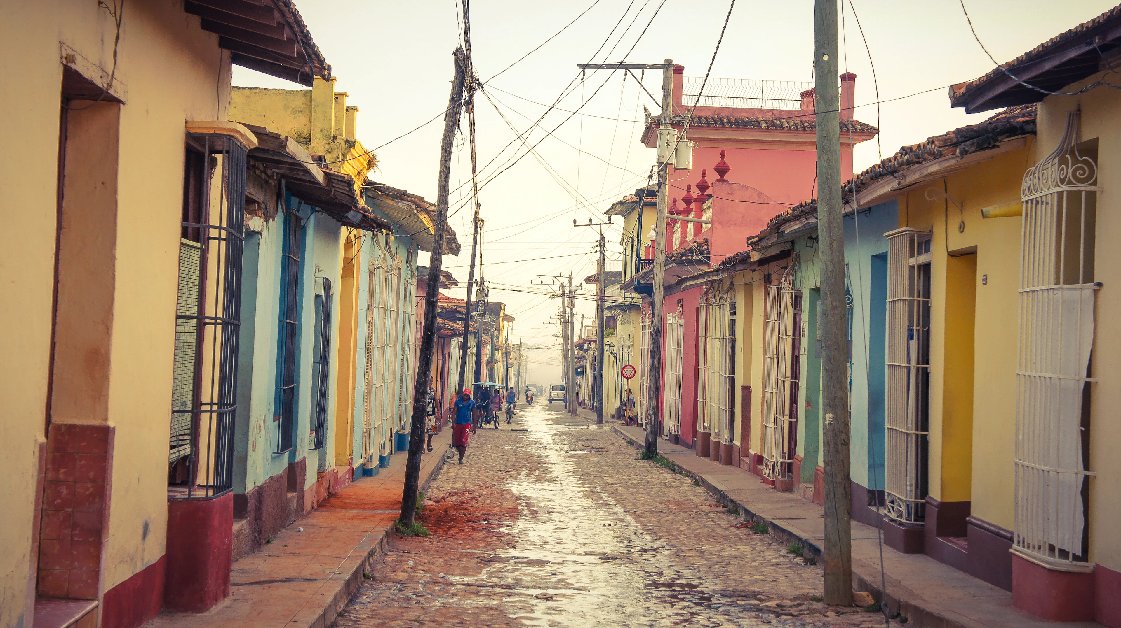 A cobbled street in Trinidad between colourful single-storey houses in morning light