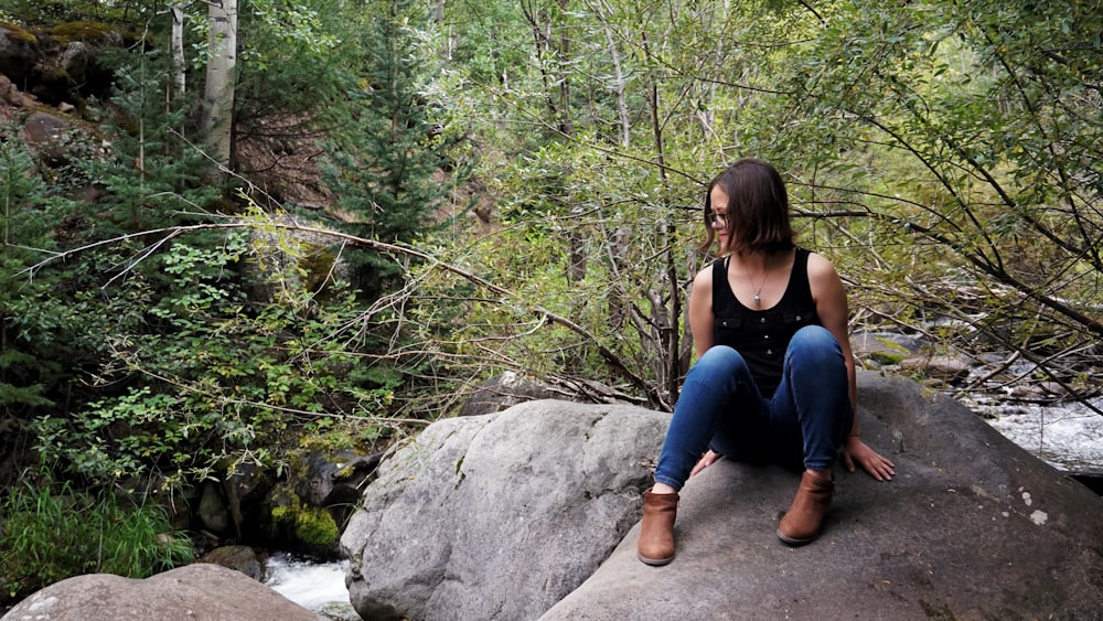 woman sitting on rock at river