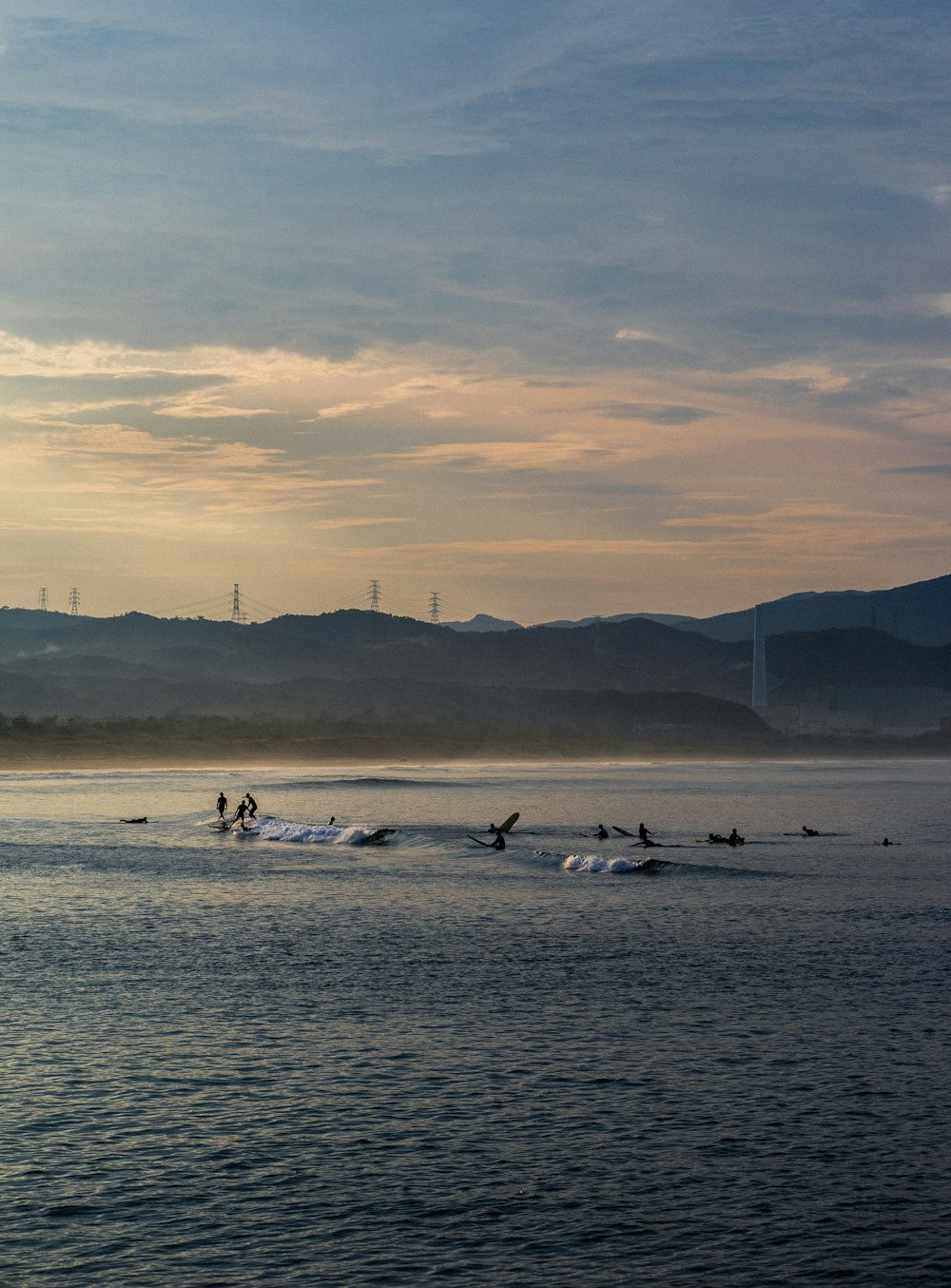 birds on body of water viewing mountain under blue and white skies during daytime