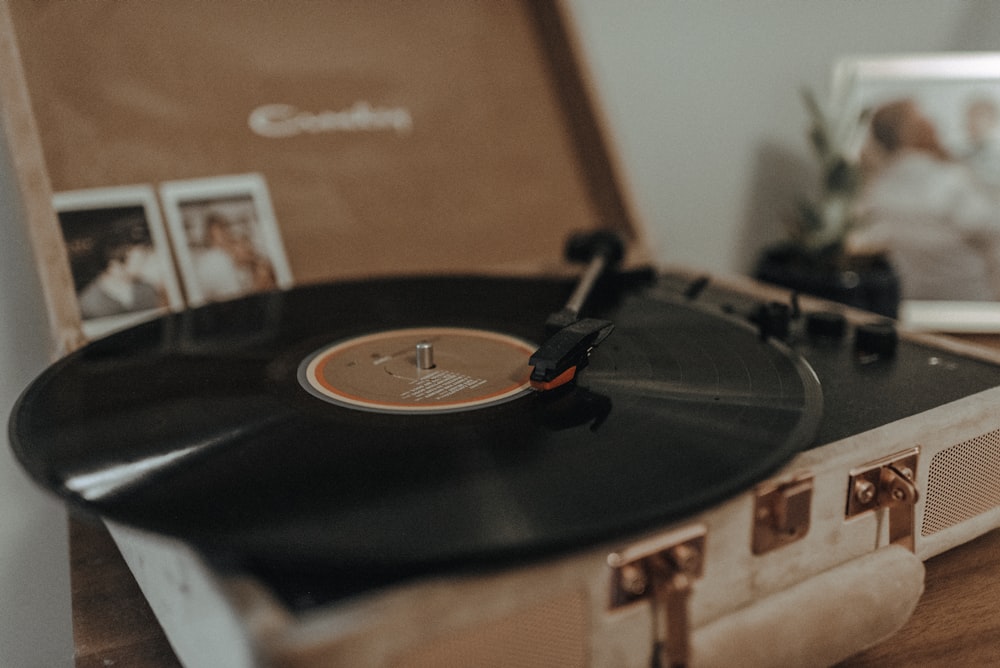 black vinyl record on brown portable turntable