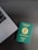 A green Nigerian passport is placed on a dark wooden table beside the corner of a laptop. The passport features gold text and a circular emblem representing the Economic Community of West African States (ECOWAS) at the center.