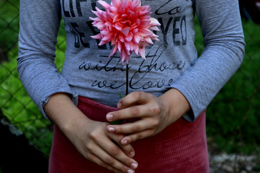 Eine Frau, die eine rosa Blume in den Händen hält