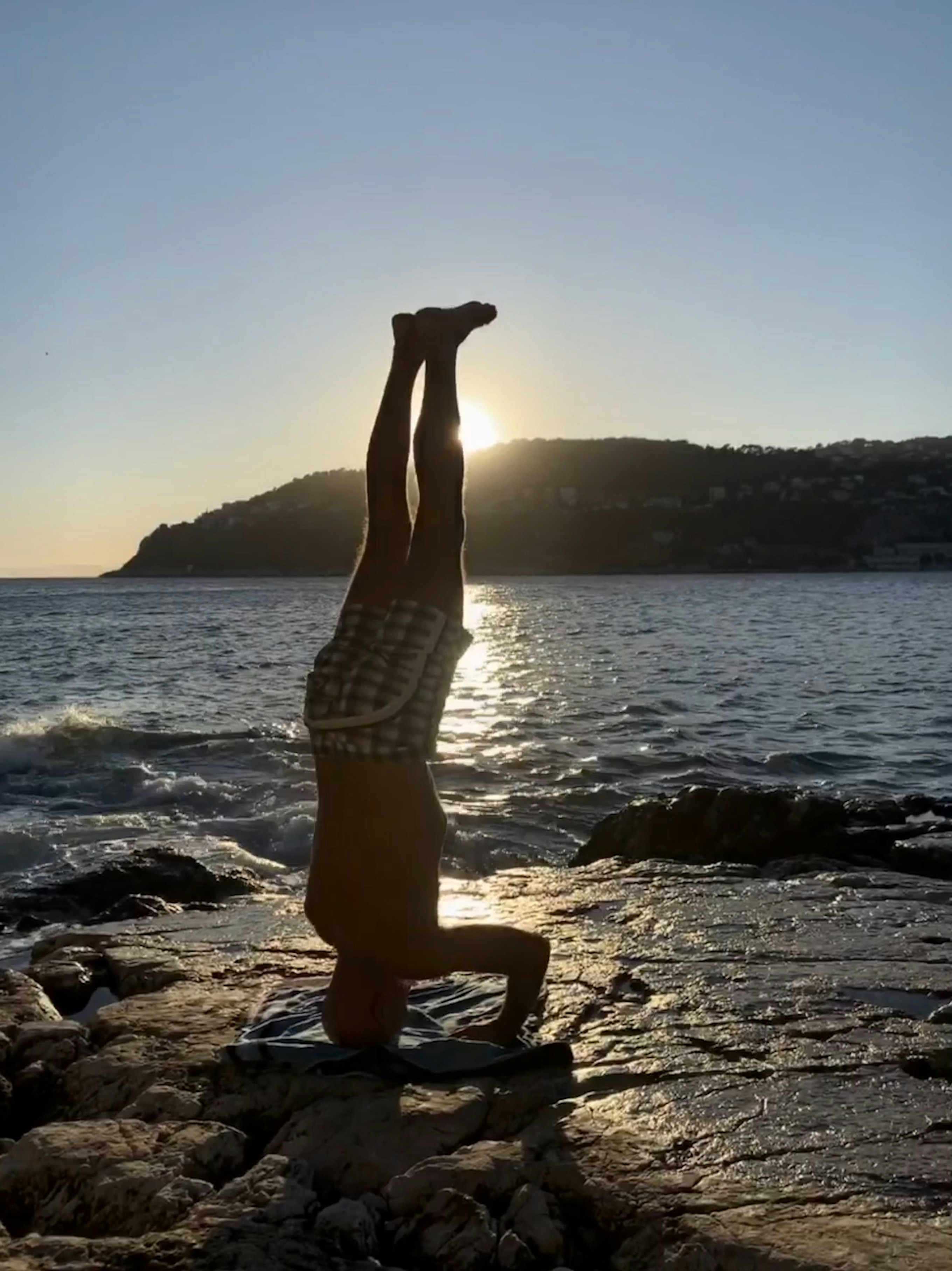 Fotografía de primer plano del hombre invirtiendo el cuerpo cerca del mar