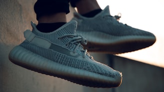 A pair of stylish sneakers with a textured design, laces, and rubber soles, shown in an outdoor setting with soft lighting.