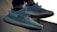 A pair of stylish sneakers with a textured design, laces, and rubber soles, shown in an outdoor setting with soft lighting.