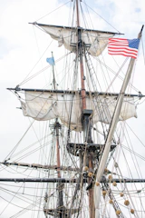 Historic sails being hoisted on the ship during restoration.