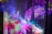 Vibrant colors and abstract patterns create a dynamic and immersive visual experience. The image features overlapping layers of translucent fabric or screens, onto which bright, saturated colors like purple, pink, green, and blue are projected. Organic shapes and abstract designs evoke a sense of movement and fluidity, possibly suggesting elements of nature or fantasy.