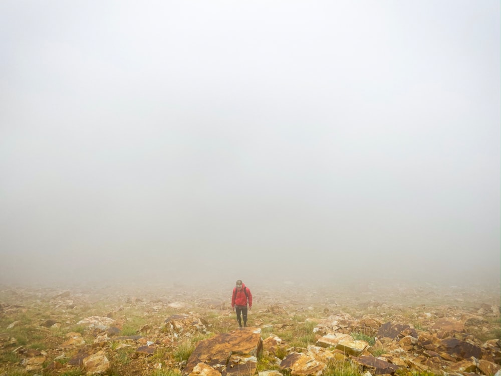 person wearing red jacket standing under foggy weather