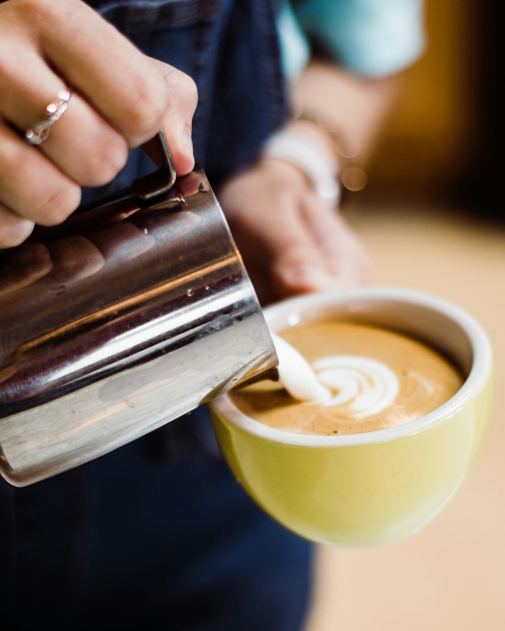 person pouring milk in cappuccino