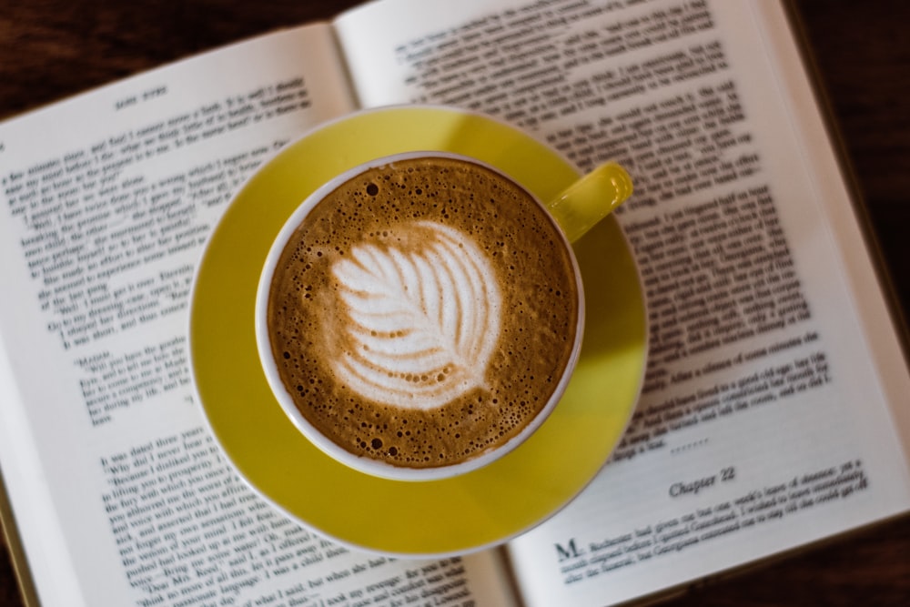 eine Tasse Kaffee, die auf einem aufgeschlagenen Buch sitzt