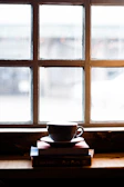 Cozy corner with a warm coffee cup and a stack of favorite books by a sunlit window.