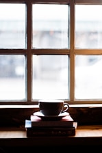 A cozy workspace with stacks of colorful children's books and a warm cup of tea by a window.