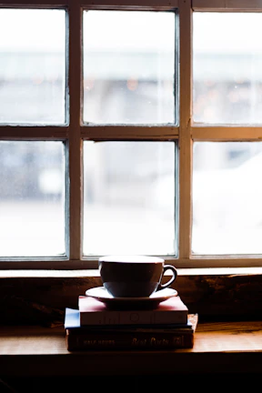 Cozy corner with a warm coffee cup and a stack of favorite books by a sunlit window.