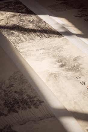 A traditional ink painting on paper depicting a serene landscape with lush trees. The brushstrokes create a sense of depth and movement. Soft shadows cast by light filtering through add an atmospheric touch.
