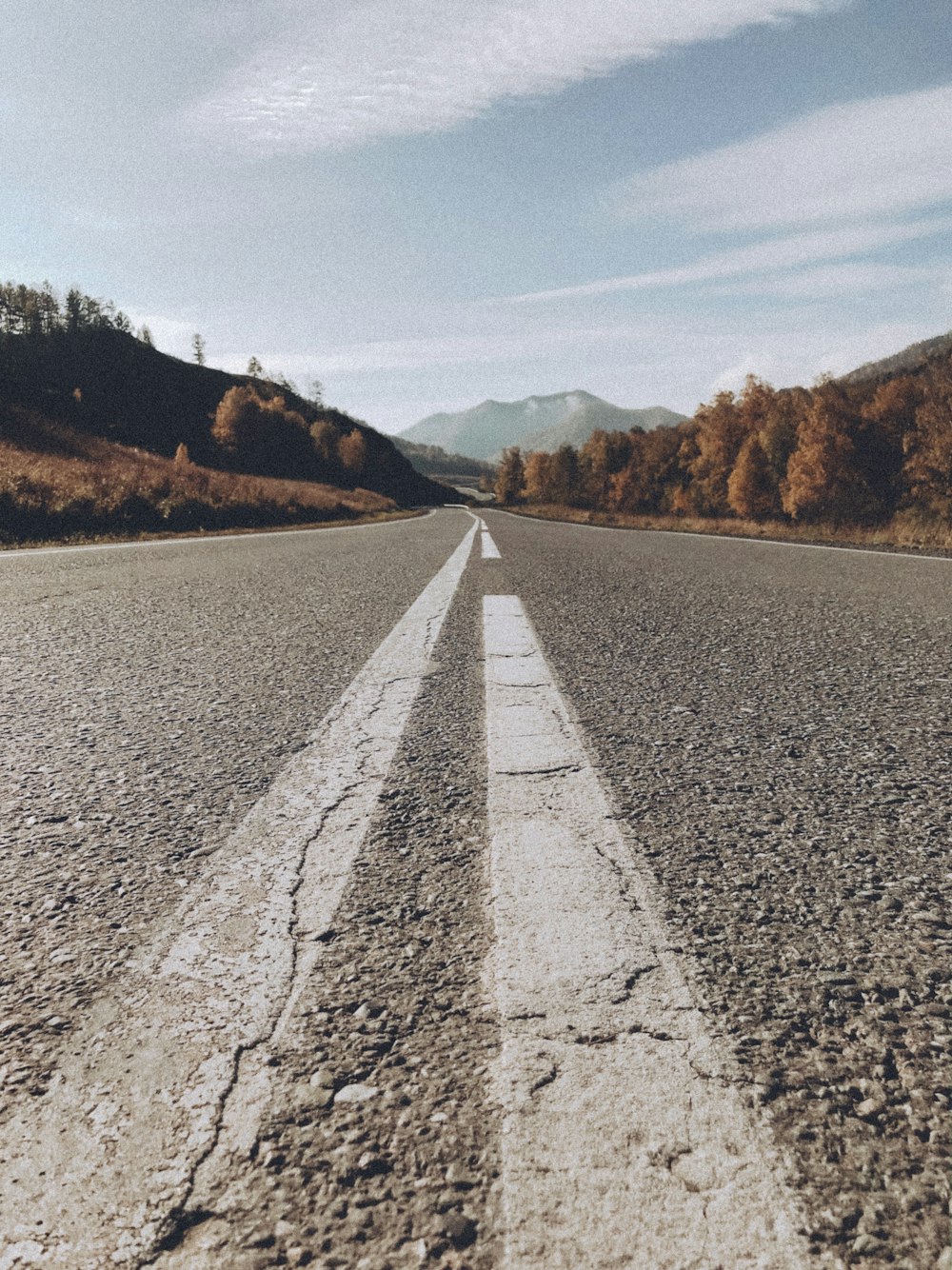 gray concrete road with no vehicle viewing mountain under white and blue skies during daytime