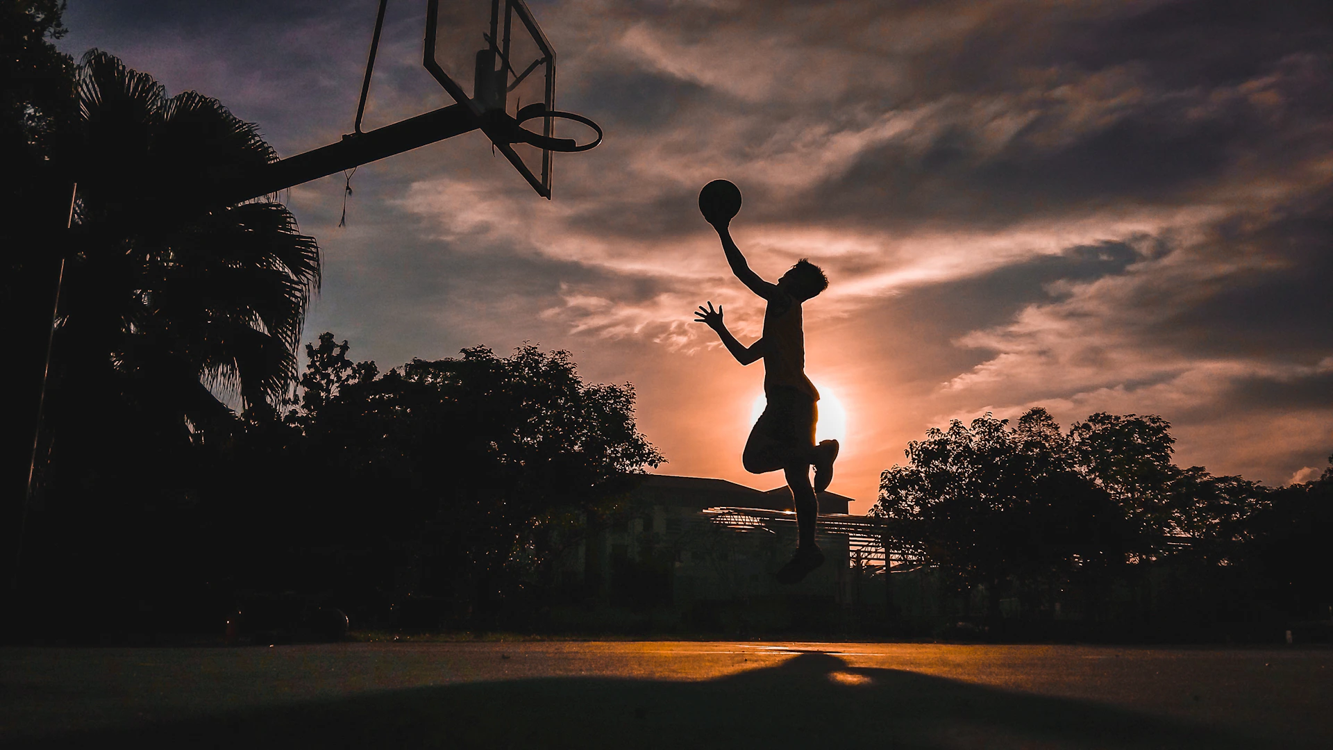 silhouette of boy jumping shooting ball