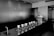 A sleek and modern coffee preparation area with multiple pour-over coffee drippers arranged in a row on a counter. There is a large coffee grinder on the right and a stainless steel faucet on the left. The environment is minimalistic, with a strong emphasis on clean lines and a monochromatic color palette.
