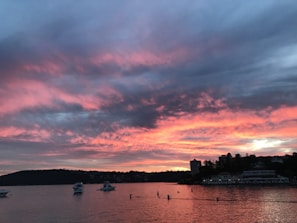 A vibrant sunset over Lake Xolotlán with colorful boats in the foreground